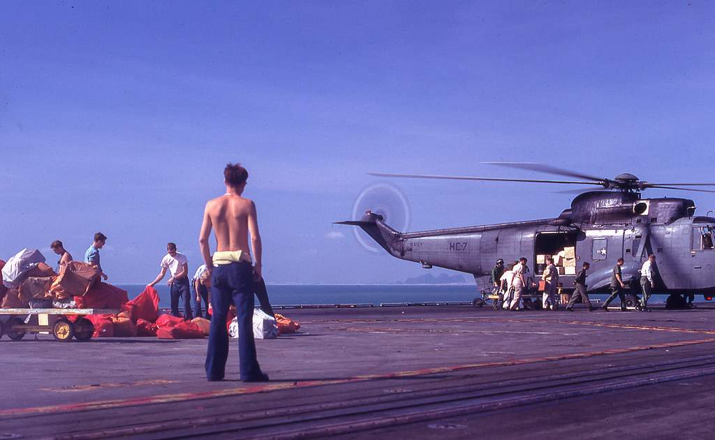 Sailors loading supplies on a helicopter aboard an aircraft carrier.